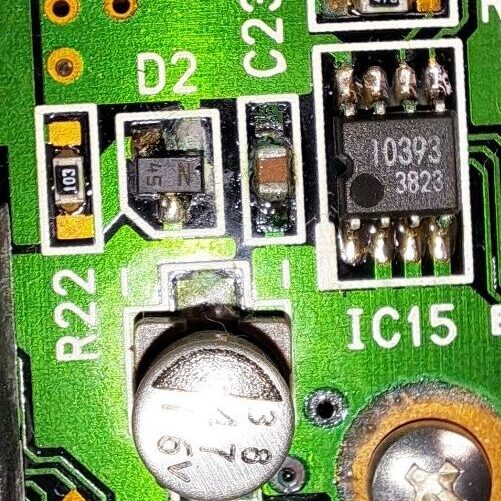 Corrosie rondom condensator C21 op een synthesizer-printplaat — zwarte koper(II)oxide-aanslag en bruine verkleuring van soldeer en laminaat door uitgelopen elektrolyt