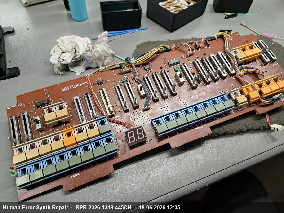 Het bruine Roland frontpaneel board met schuifregelaars, drukknoppen en 7-segment display, losgenomen op de werktafel.