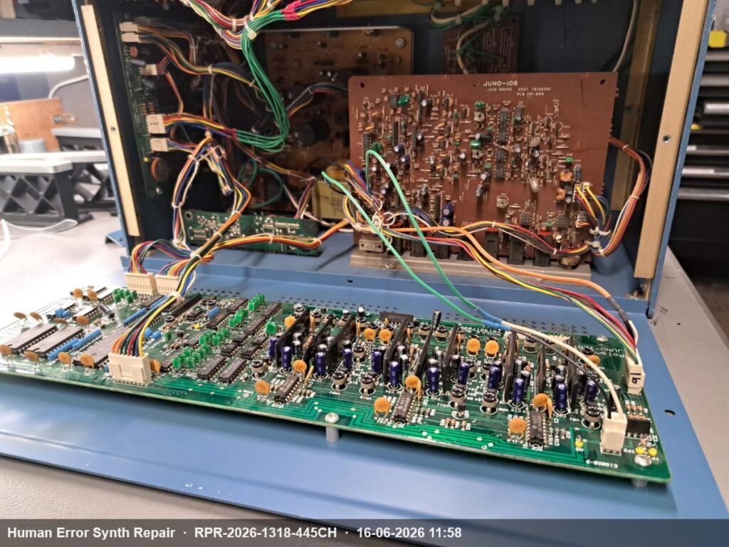 Module board van de Juno-106 opengeslagen in de rackbehuizing, met jack board en uitgebreide bedrading zichtbaar op de achtergrond.