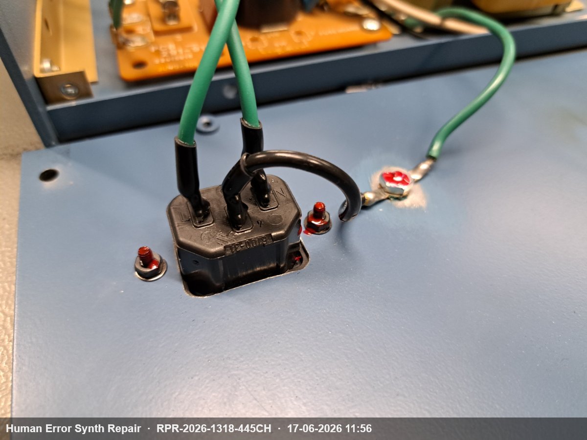 Nieuwe zwarte AC-voedingsconnector gemonteerd in de blauwe rackbehuizing, met groene aardingsdraad en zwarte voedingsdraden.