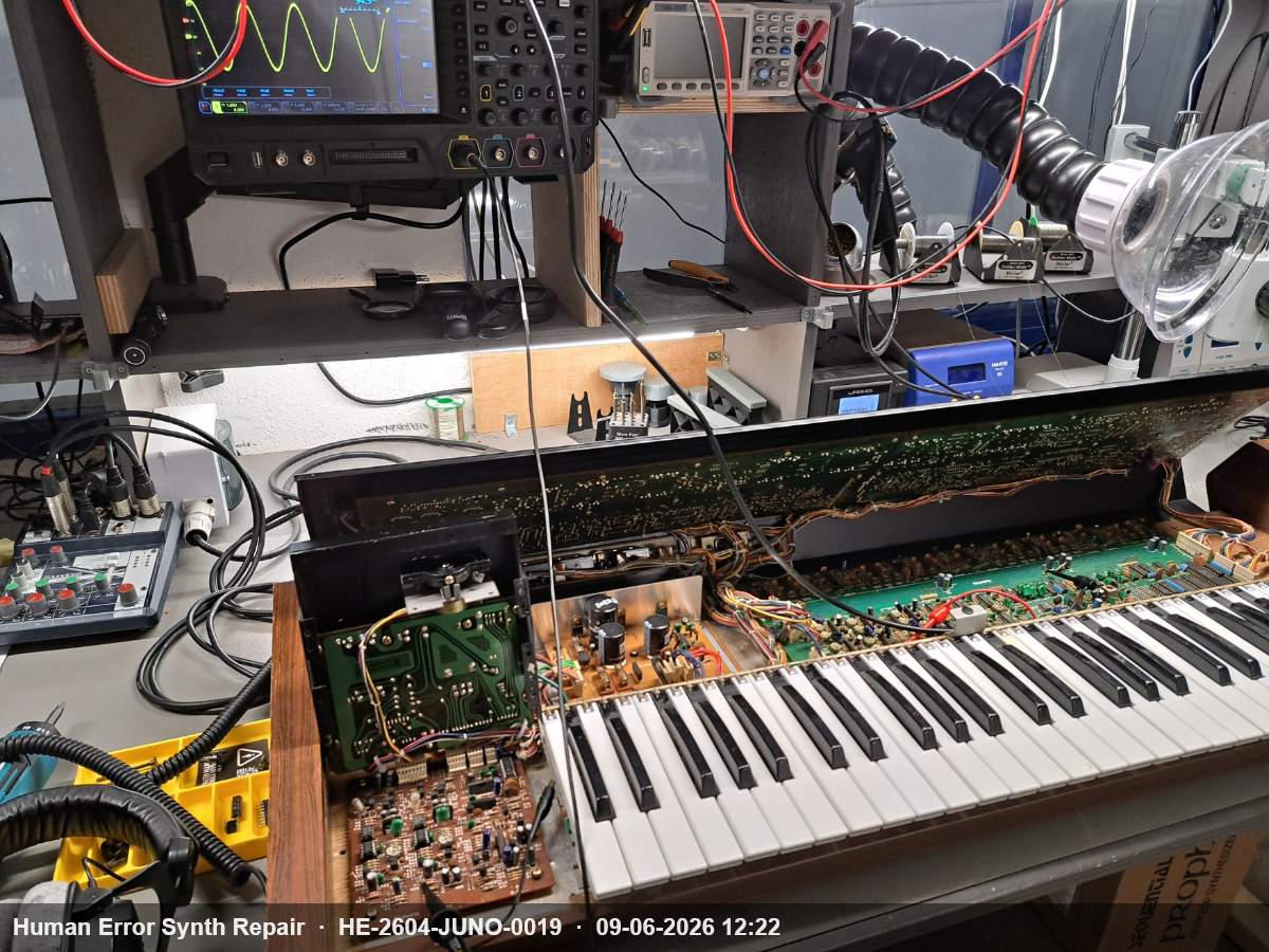 Roland Juno-60 opengeslagen op de werkbank met oscilloscoop op de achtergrond die een sinusgolf toont tijdens bias-afregeling.