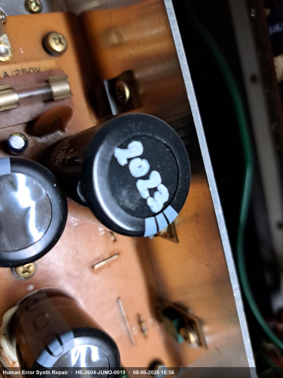 Close-up van grote elektrolytische condensatoren op de voedingsplaat met datumstempel '2023' zichtbaar op de behuizing.