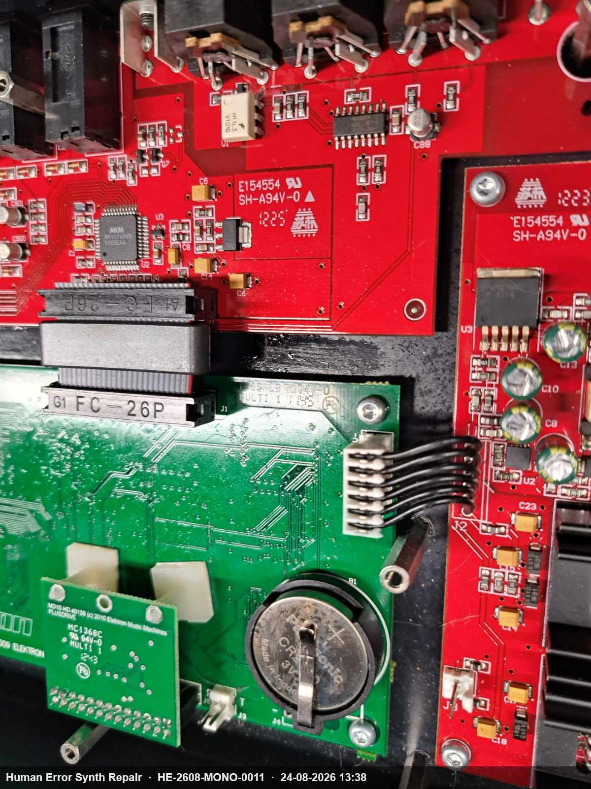 Groen CPU-board met zichtbare CR2450-knoopcelbatterij en grote FC-26P IDC-connector naast rode synthesizer-printplaten.