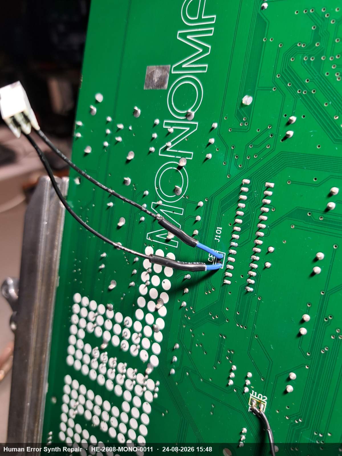 Onderzijde van het groene Monomachine-board met opnieuw aangesloten draden bij connector J101, waarvan één draad een blauwe kern toont.