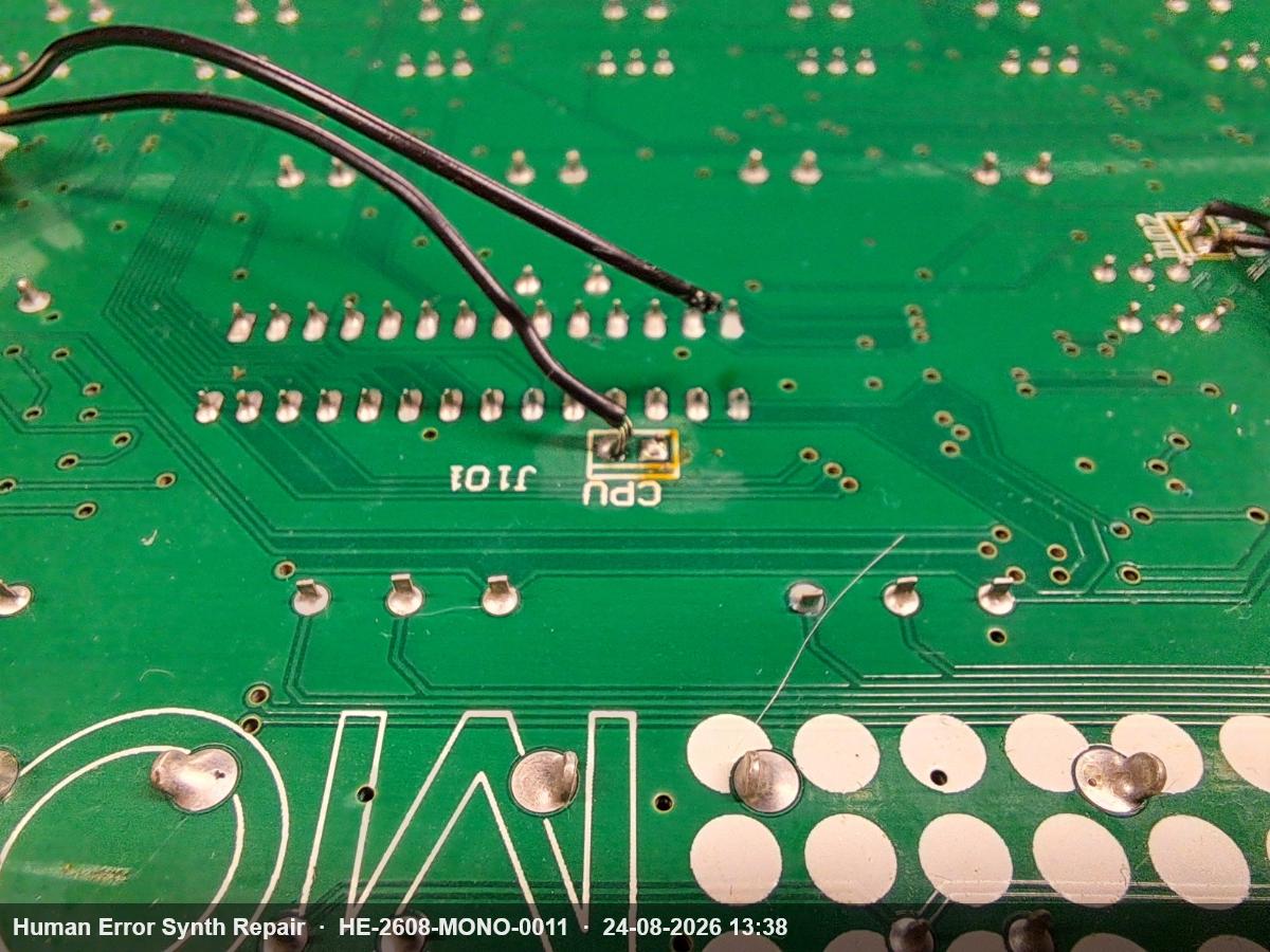 Onderzijde van een groene printplaat met twee losgeraakte zwarte draden bij connector J101 naast de CPU-aanduiding.