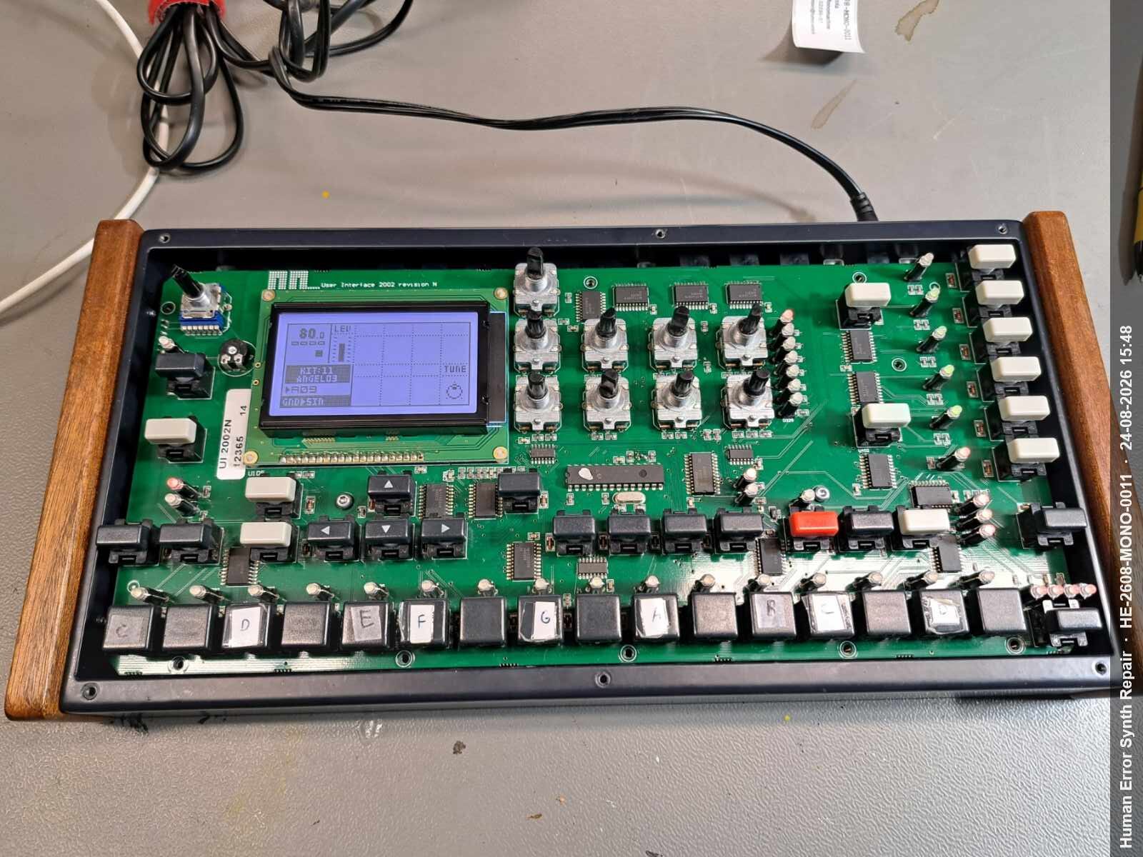 Groen UI-board van de Monomachine liggend op de werktafel, display toont de tune-pagina tijdens opgestart systeem.